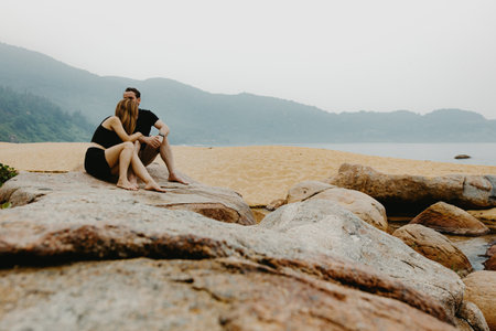 Caucasian couple enjoying tranquil beach moments on rocky shoreline.の写真素材