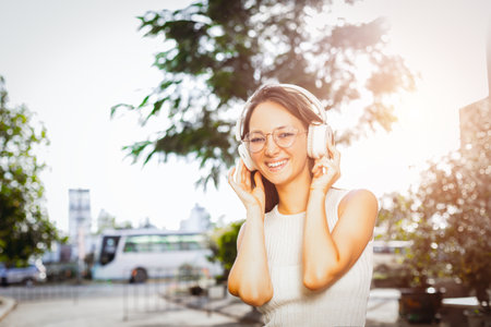 Young caucasian female enjoying music outdoors with headphones.の写真素材