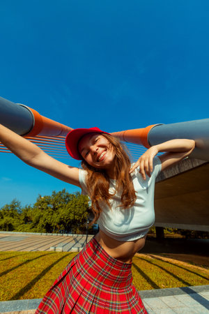Cheerful young caucasian female in tartan skirt enjoying sunny day outdoors.の写真素材