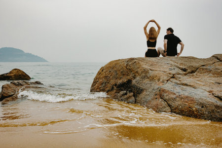 Young caucasian couple enjoying beachside view on rocks.の写真素材