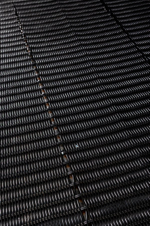 Close-up of intricate black woven metal pattern creating geometric texture.の写真素材