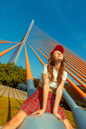 Young caucasian female enjoying sunny day on modern bridge structure.の写真素材