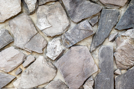 Close-up of stone wall with varied textures and shapes for natural background.の写真素材