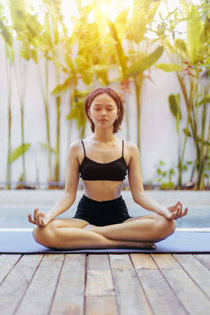 Asian young female practicing yoga outdoors in meditation pose.の写真素材