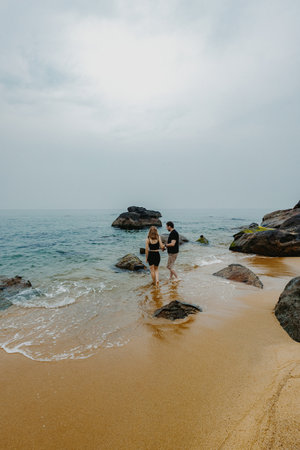 Young caucasian couple enjoying serene beach walk by the ocean.の写真素材