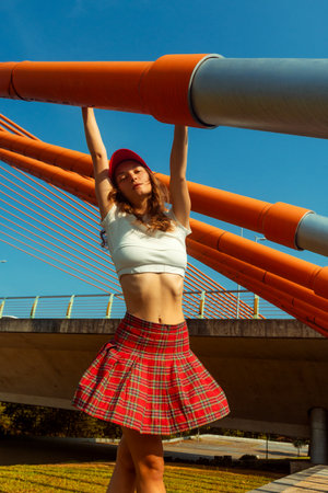 Young caucasian woman in red skirt and cap posing on bridge.の写真素材