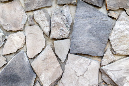 Rustic stone wall texture with irregular gray and beige rocks.の写真素材