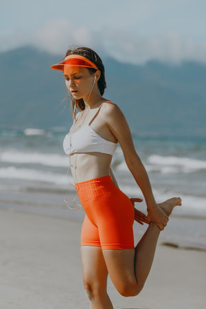 Young caucasian female stretching on beach in activewear.の写真素材