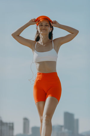 Young asian female jogger in bright athletic outfit enjoying urban exercise.の写真素材