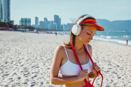 Young asian female enjoying music on beach with headphones.の写真素材