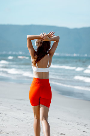 Young caucasian female enjoying a beach walk in red shorts and white top.の写真素材