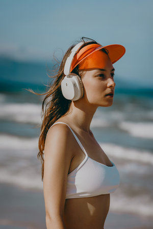 Young caucasian female enjoying music on beach with headphones and visor.の写真素材