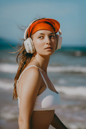 Young caucasian female enjoying music on beach with headphones and visor.の写真素材
