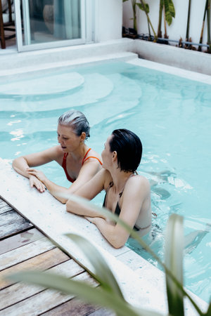 Mature caucasian women enjoying relaxing swim in pool.
