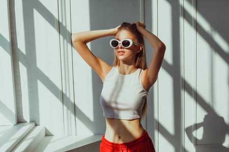 Young caucasian female in sunglasses relaxing in sunlit room.の写真素材