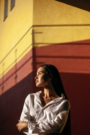 Young hispanic woman in white shirt posing against colorful urban wall.の写真素材
