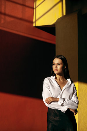 Young caucasian female in white shirt posing against colorful geometric background.の写真素材