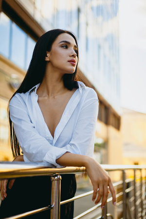 Confident asian young female in white shirt posing outdoors on urban balcony.の写真素材