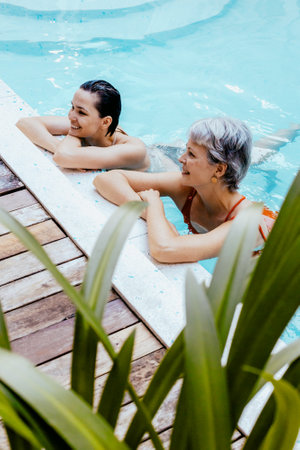 Caucasian females relaxing in pool - young adult and mature woman enjoying leisure time.の写真素材