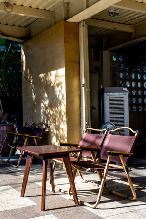 Sunny outdoor patio seating with wooden chairs and table.の写真素材