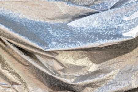 Crumpled metallic texture with shimmering silver and gold tones.の写真素材