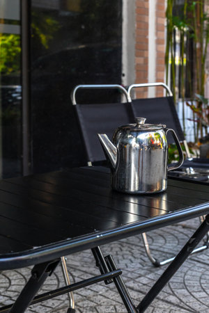 Stainless steel teapot on outdoor black metal table.の写真素材