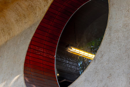 Circular window with red tiles and industrial light fixture in architectural design.の写真素材