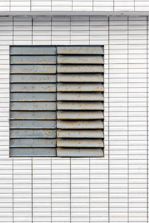 Rusty metal louvered window on white tiled wall surface texture and pattern.の写真素材