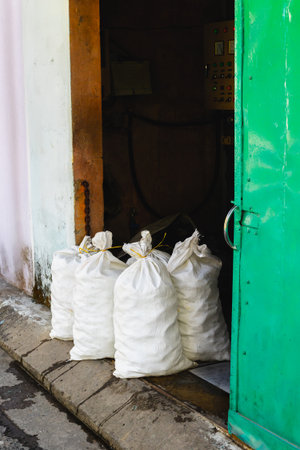 Four large white sacks by an open green doorway in an industrial setting.の写真素材