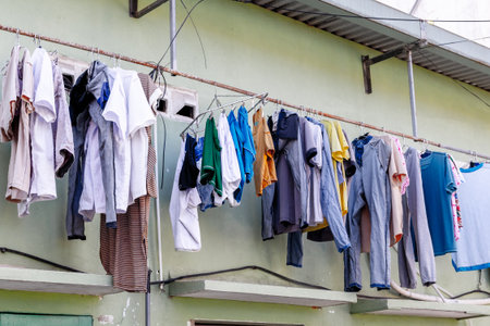 Assorted laundry hanging outdoors on clothesline against wall.の写真素材