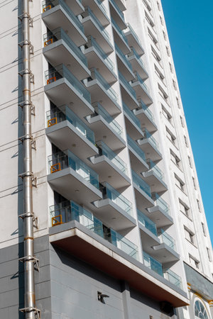 Modern high-rise building with multiple balconies under clear blue sky.の写真素材