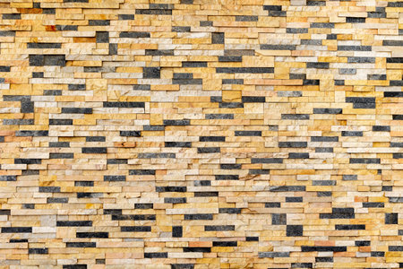 Textured yellow and black stone wall with brick pattern.の写真素材