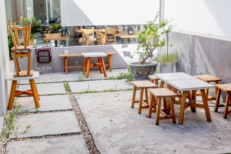 Cozy outdoor cafe patio with wooden furniture and potted plant.の写真素材