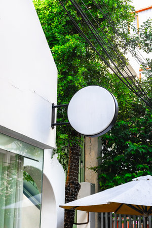 Blank round sign on building facade with greenery.の写真素材