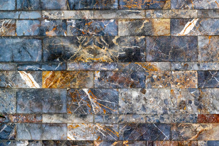 Textured natural stone wall with varied colors and patterns.の写真素材