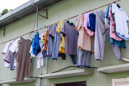 Variety of clothes drying on outdoor clothesline against green wall.の写真素材