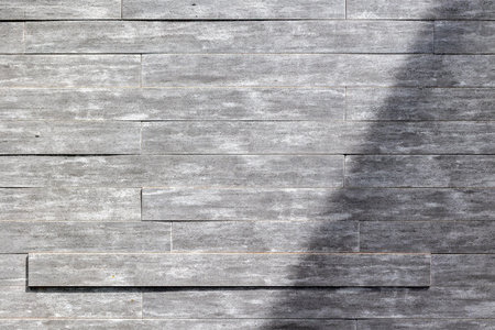 Textured gray stone wall with natural pattern and shadow play.の写真素材