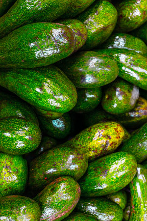 Fresh green avocados stack with varied textures and glossy finish.