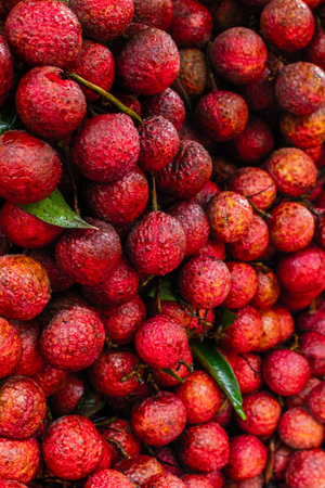 Close-up of fresh red lychee fruit cluster with green leaves.