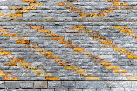Patterned brick wall with gray and orange textured stone design.の写真素材