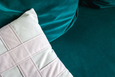 White textured pillow on teal velvet couch close-up interior design.の写真素材