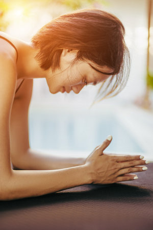 Asian young female practicing relaxation techniques by the poolside.の写真素材