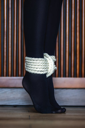 Rope binding on feet with black stockings indoors.の写真素材