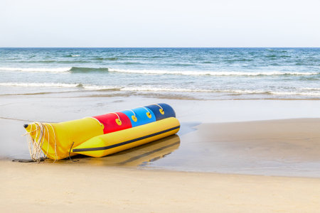 Colorful inflatable banana boat on quiet sandy beach by the ocean.の写真素材