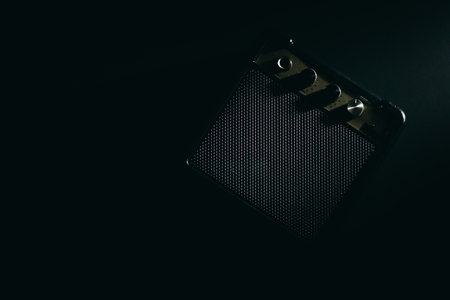 Black guitar amplifier against dark background with metallic knobs.の写真素材