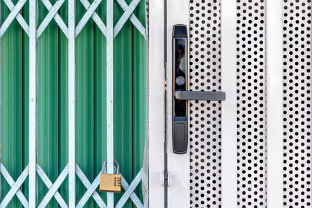 Green metal gate with padlock and white perforated door handle detail.