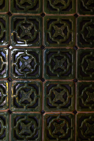 Intricate green ceramic tiles with floral patterns and glossy finish.