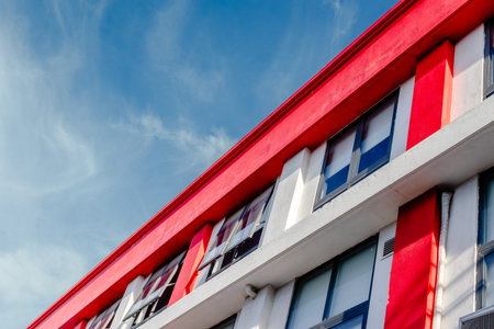 Modern red and white building against blue sky with cloud streaks.の写真素材