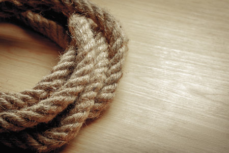 Coiled jute rope on wooden surface with natural texture and soft lighting.