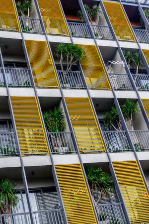 Modern urban apartment building with yellow facade and metal railings.